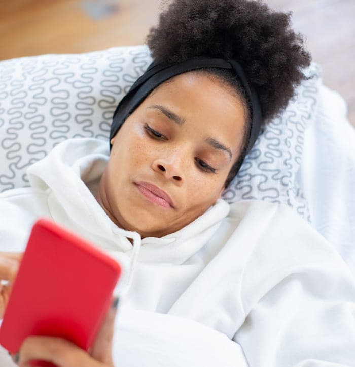 Unwell woman searching for care on her phone in bed